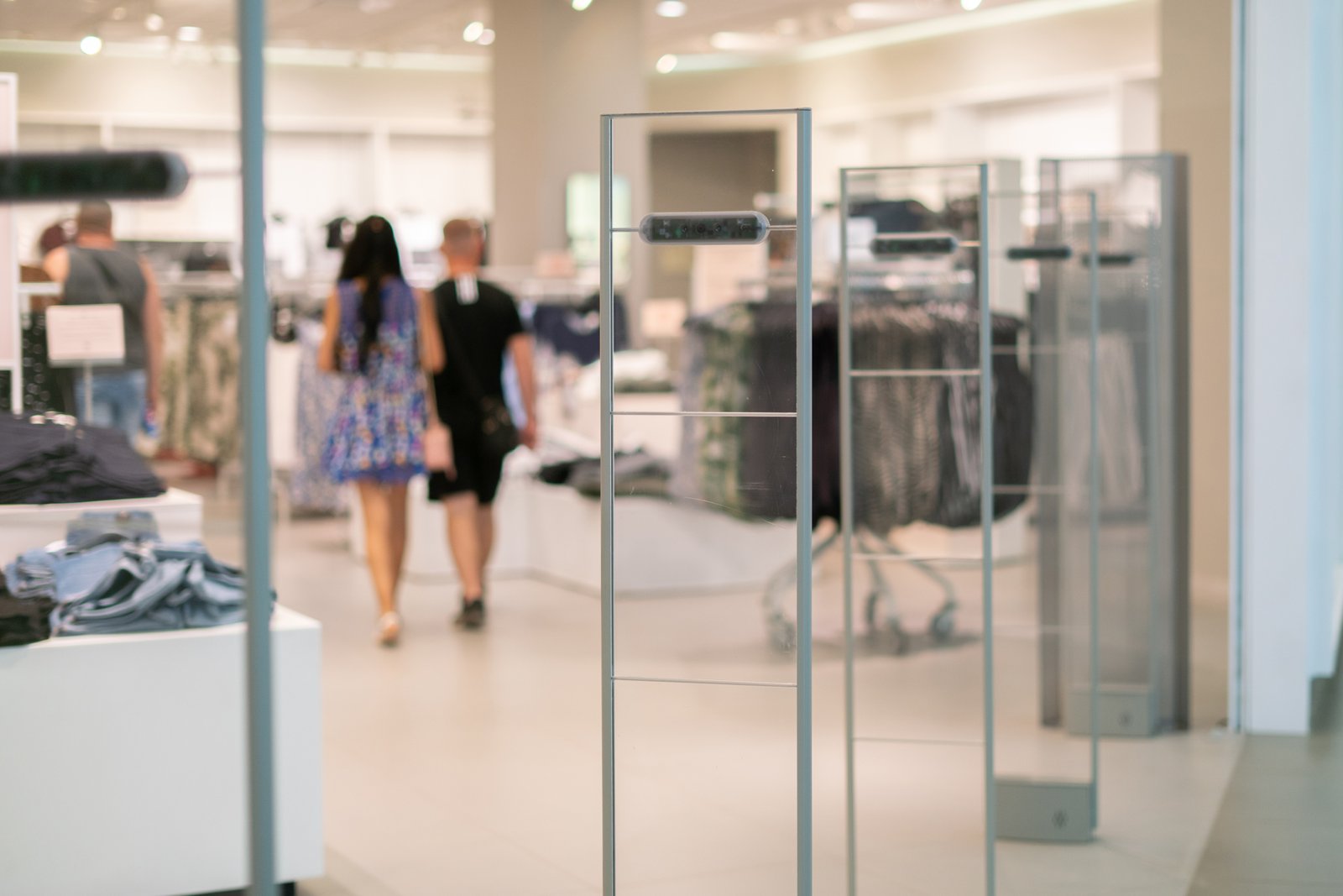Antenas de seguridad anti-robo en la entrada de una tienda de ropa. Al fondo se observan prendas colgadas en estantes. Las antenas están diseñadas para detectar etiquetas de seguridad en productos y prevenir el robo.