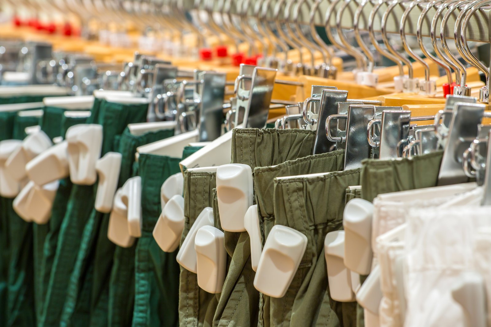 Ropa colgada en perchas con dispositivos de seguridad adheridos a cada prenda, utilizada para la prevención de robos en tiendas de retail.